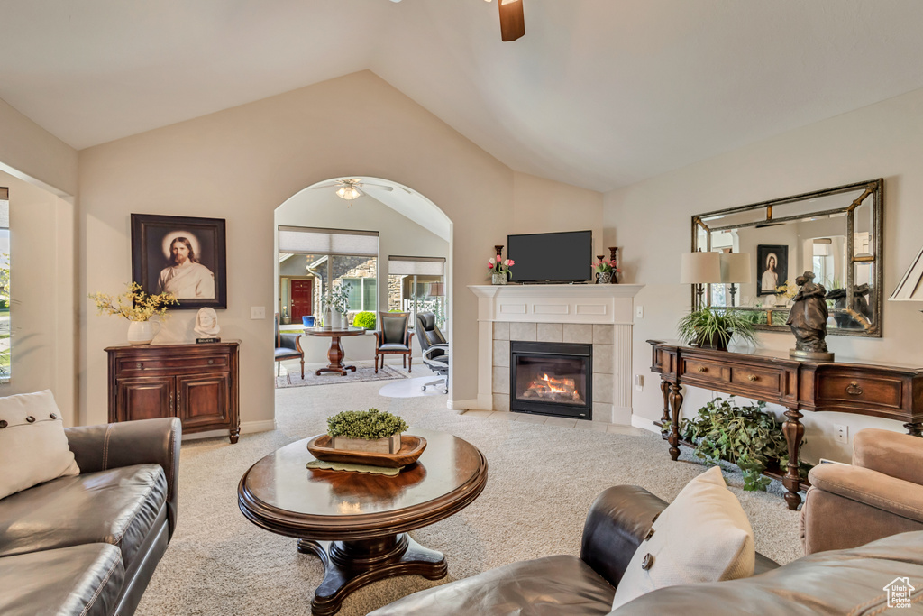 Living area with a ceiling fan, carpet, lofted ceiling, and a fireplace