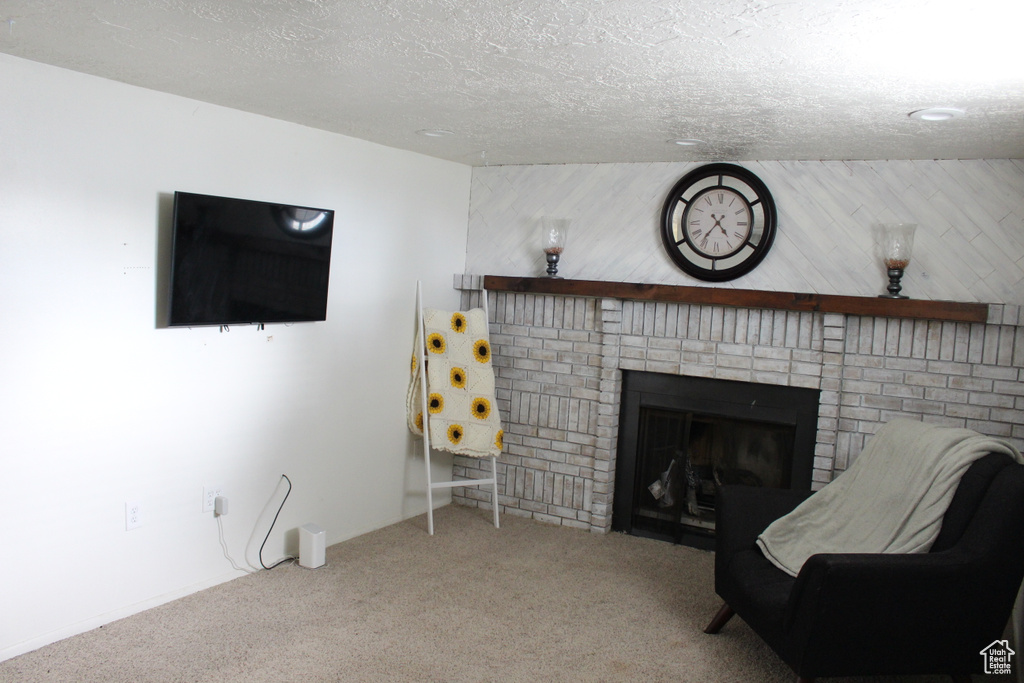 Carpeted living area featuring a brick fireplace and a textured ceiling