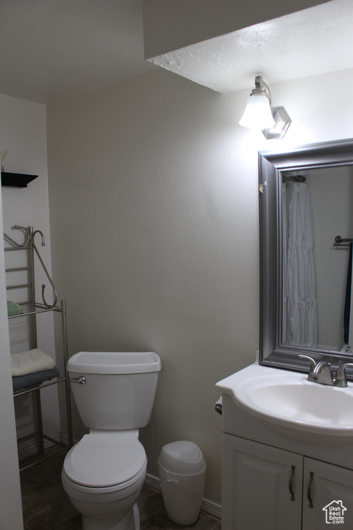 Bathroom with toilet, baseboards, and vanity