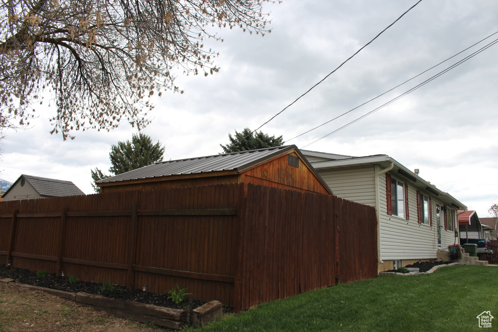 View of side of property featuring fence and a yard