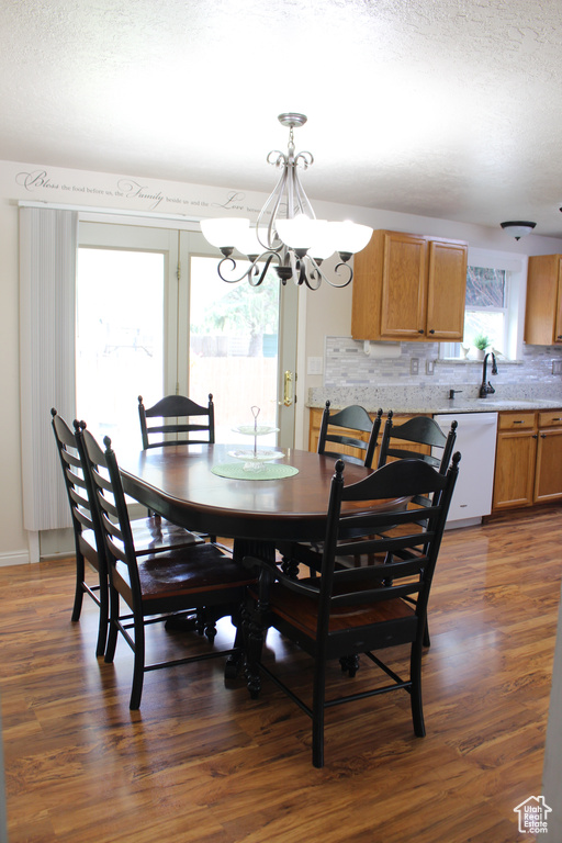Dining room featuring an inviting chandelier, a textured ceiling, and dark wood-type flooring