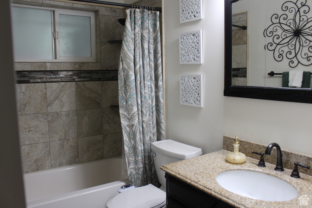 Full bath with vanity, toilet, and shower / bath combo with shower curtain