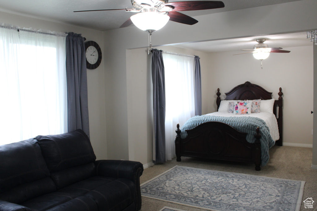 Bedroom with light colored carpet, a ceiling fan, and baseboards