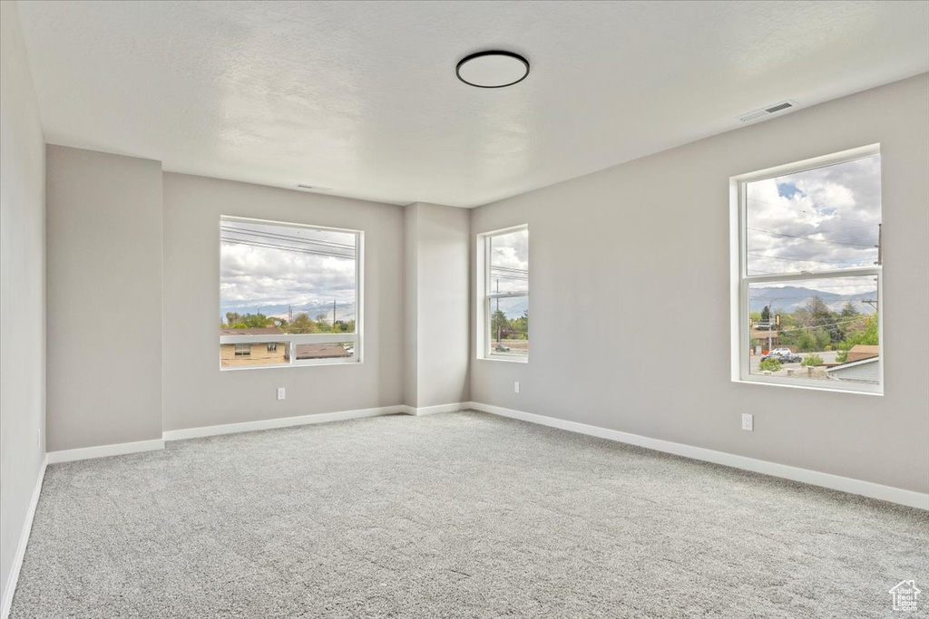 Empty room with baseboards, visible vents, a mountain view, and carpet