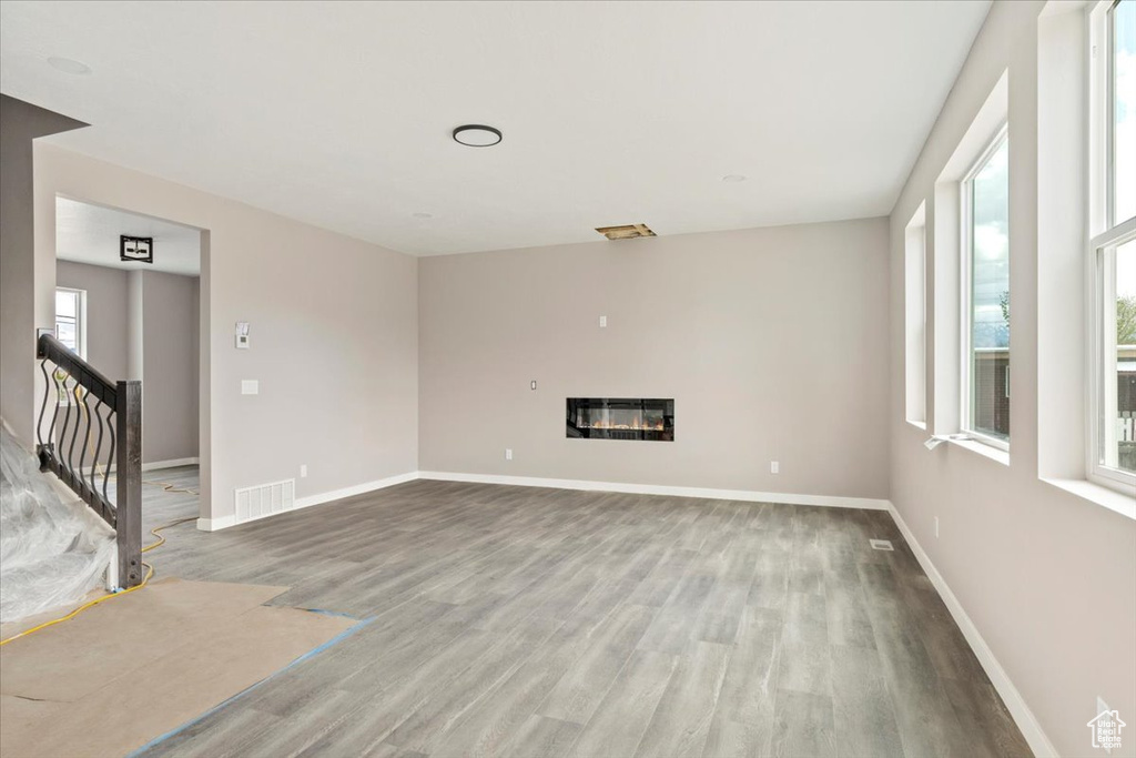 Unfurnished living room with a glass covered fireplace, baseboards, and wood finished floors