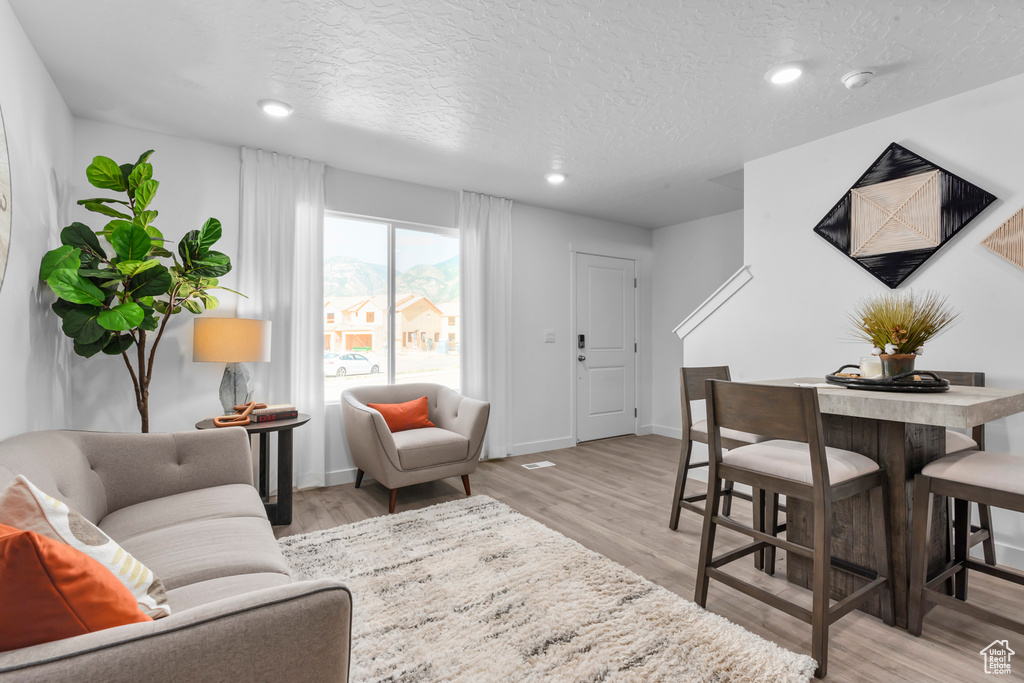 Living area with recessed lighting, a textured ceiling, light wood finished floors, and baseboards