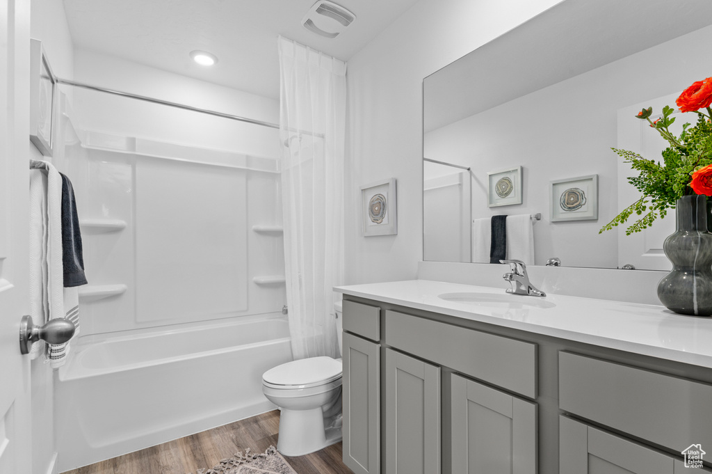 Bathroom with shower / bath combo, vanity, toilet, wood finished floors, and visible vents