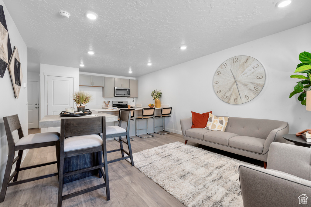 Living area featuring recessed lighting, a textured ceiling, baseboards, and light wood-type flooring