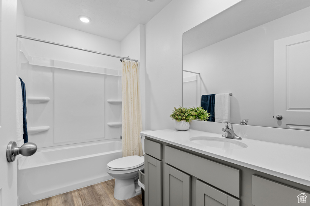 Full bathroom featuring wood finished floors, shower / tub combo, vanity, toilet, and recessed lighting