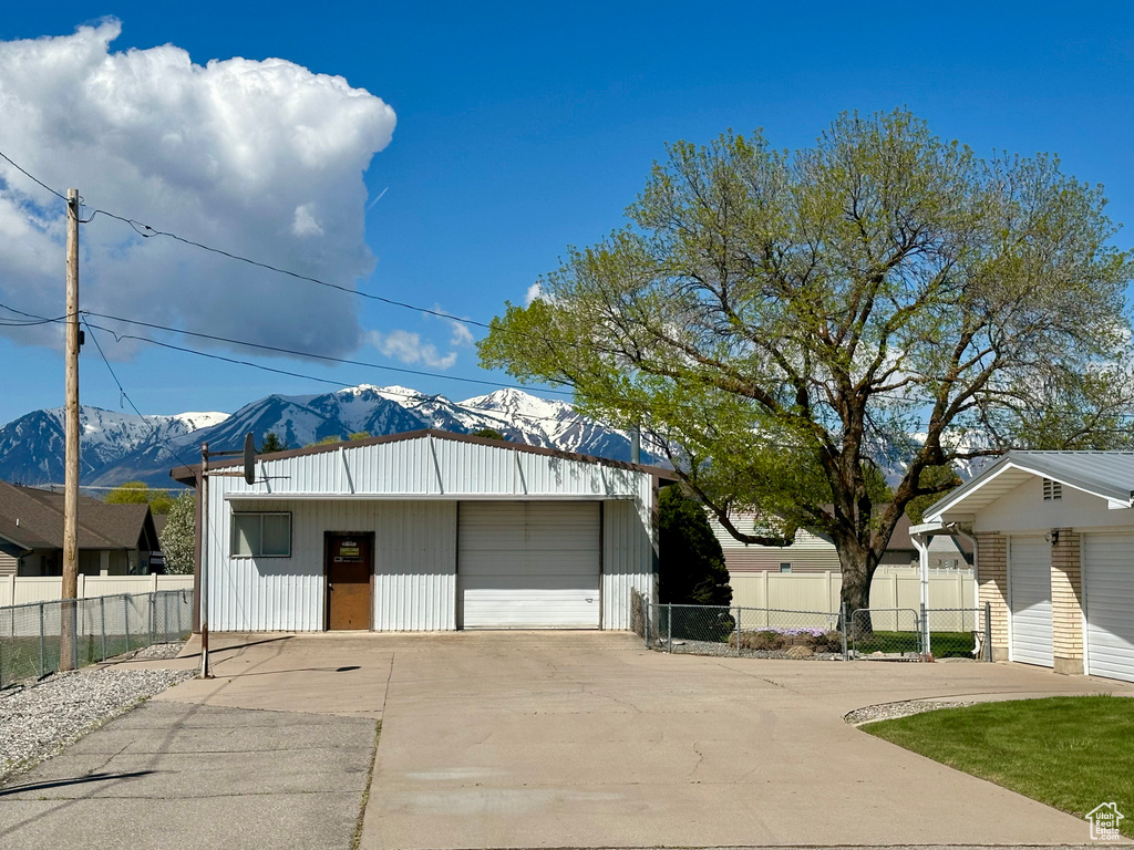 Detached garage featuring fence, a mountain view, and driveway