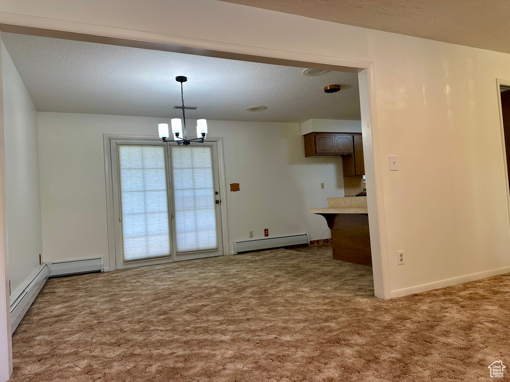 Unfurnished dining area with carpet floors, baseboards, a textured ceiling, a baseboard heating unit, and a chandelier