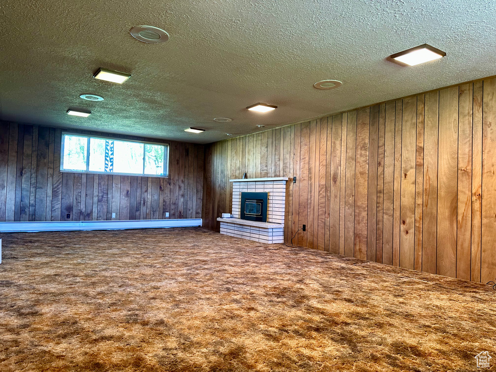 Unfurnished living room with carpet floors, a textured ceiling, and wood walls