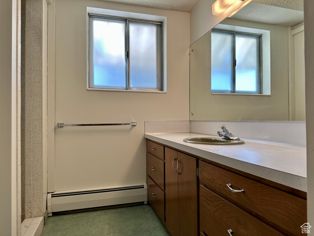 Bathroom featuring vanity, a shower, and baseboard heating