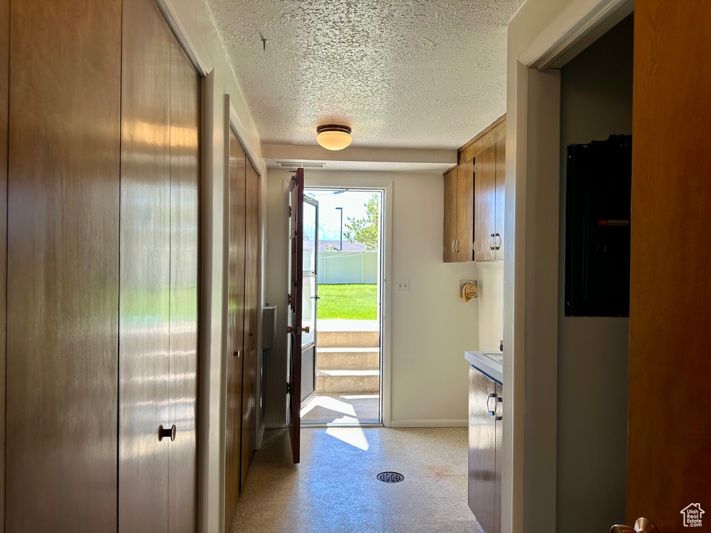Doorway to outside with baseboards and a textured ceiling
