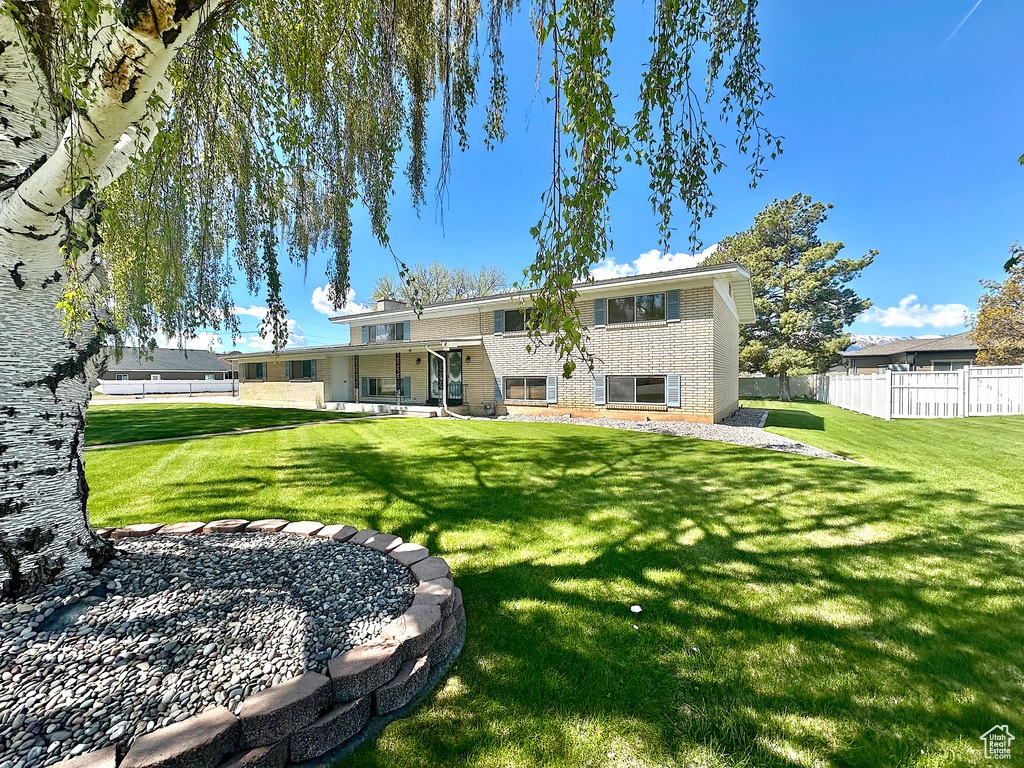 Rear view of house with a yard, brick siding, fence, and a patio