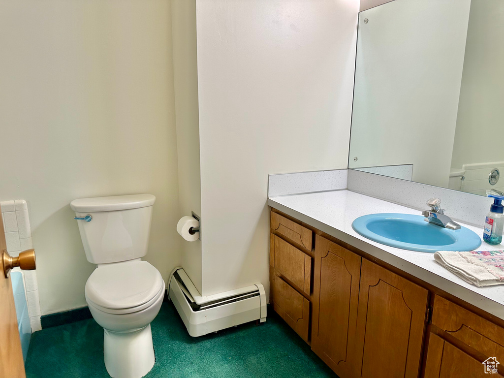 Half bathroom with vanity, baseboards, baseboard heating, and toilet