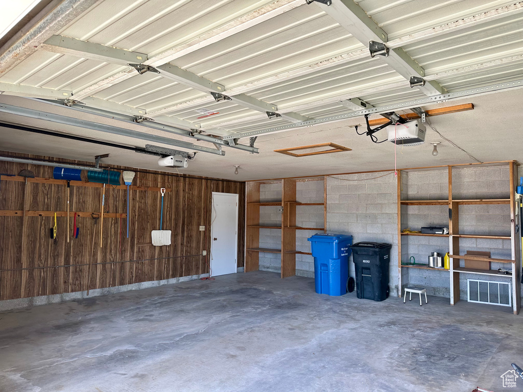 Garage with a garage door opener and wood walls
