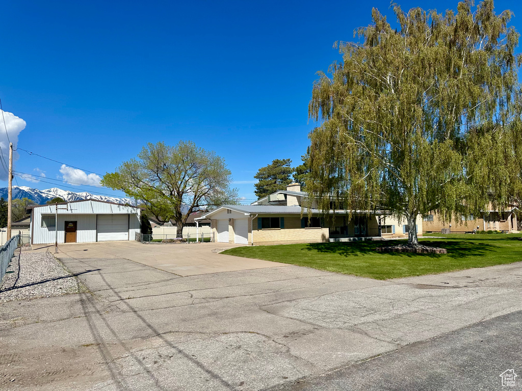View of front of property featuring fence, driveway, and a front yard