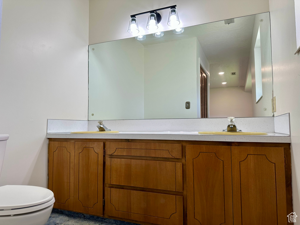 Full bathroom with a sink, toilet, double vanity, and visible vents