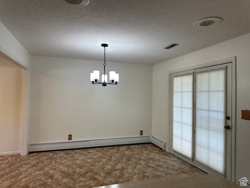 Unfurnished dining area with a notable chandelier, carpet, and a baseboard radiator