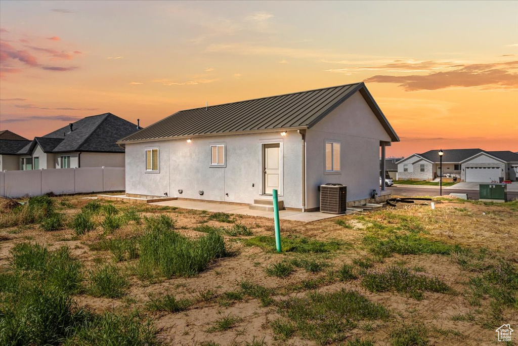 Back of property featuring central AC, a standing seam roof, metal roof, and stucco siding
