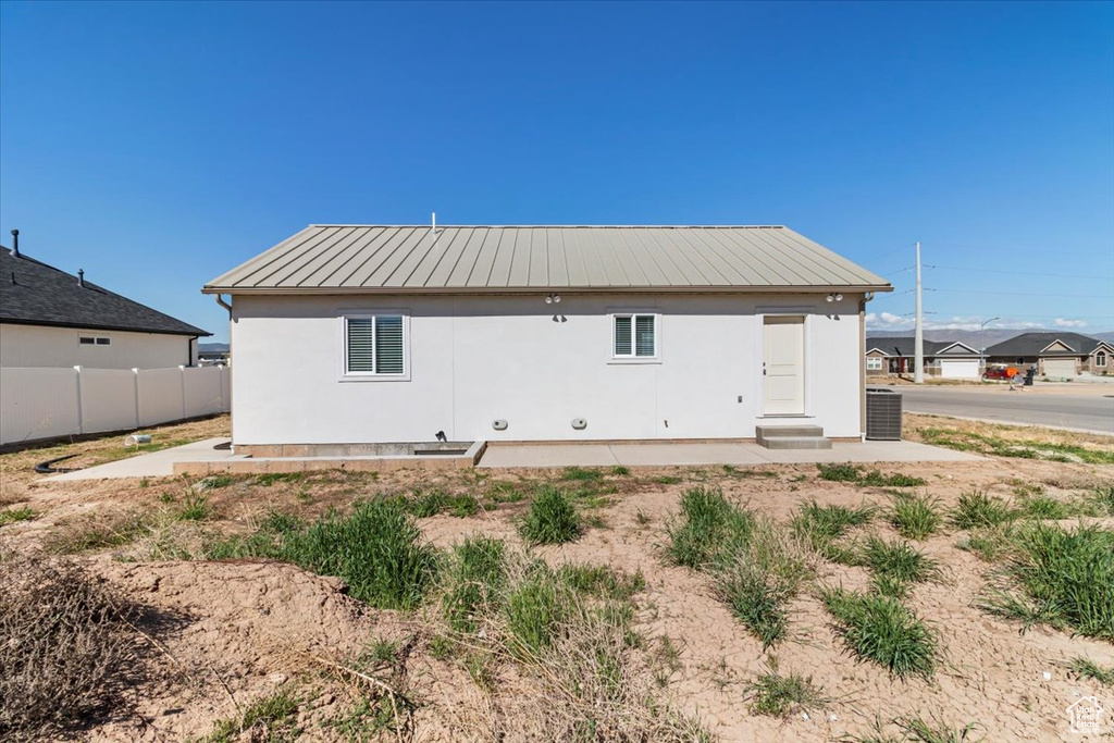 Back of property with fence, stucco siding, and metal roof