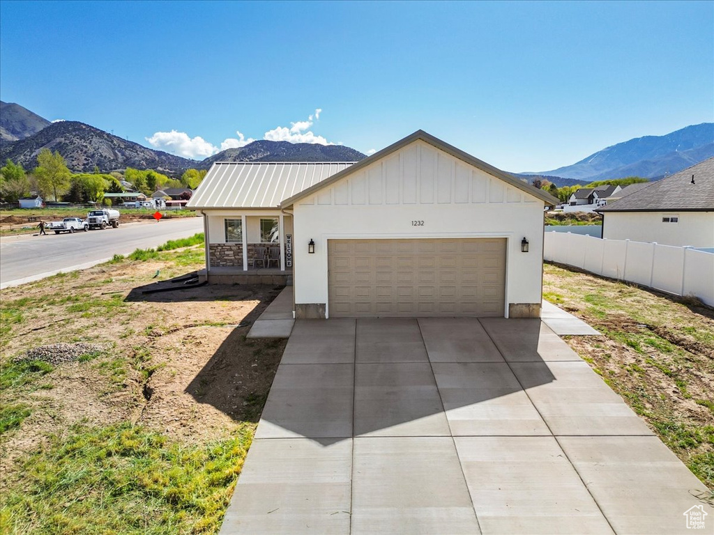 View of front of house featuring board and batten siding, driveway, fence, a mountain view, and an attached garage