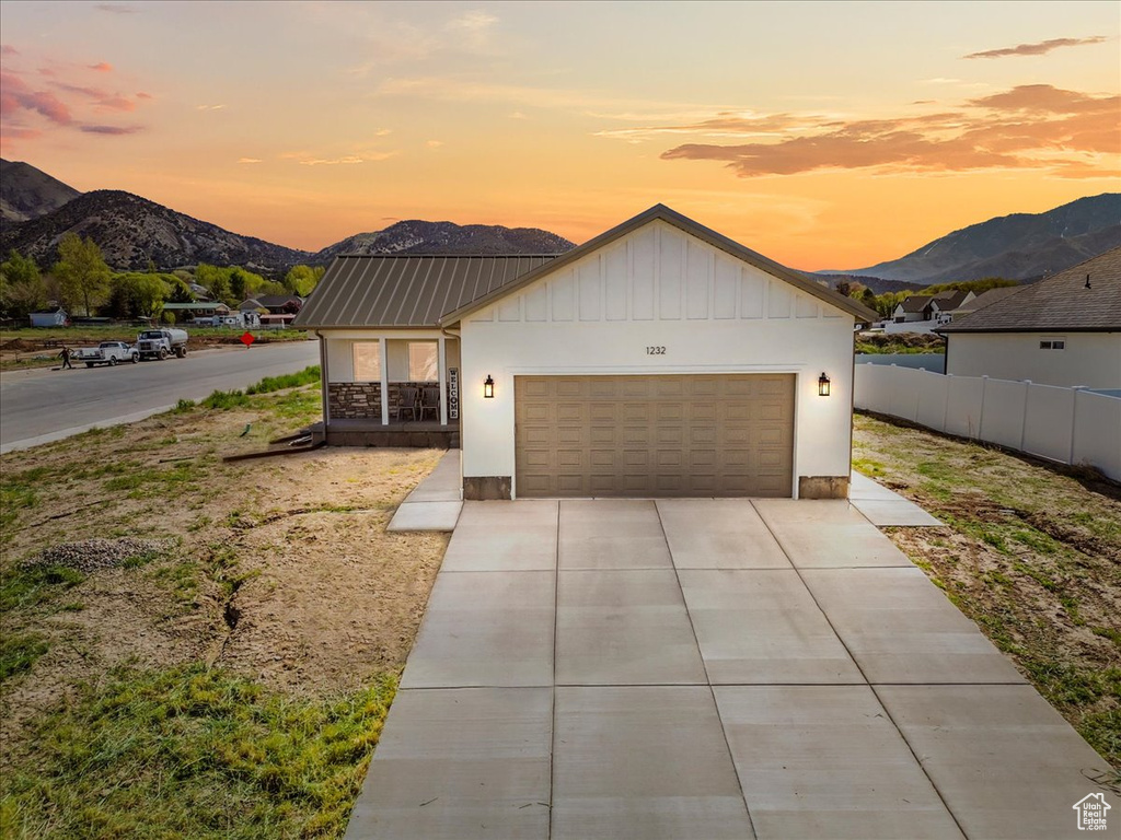 View of front of property with a garage, fence, board and batten siding, a mountain view, and driveway