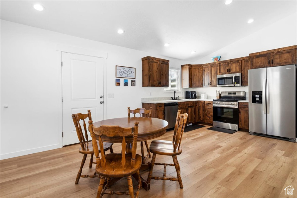 Kitchen with lofted ceiling, light wood-type flooring, light countertops, a sink, and appliances with stainless steel finishes