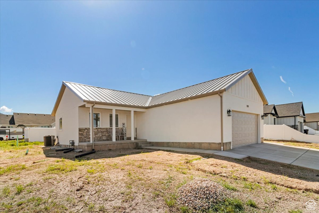View of front of property with metal roof, a garage, covered porch, and a standing seam roof