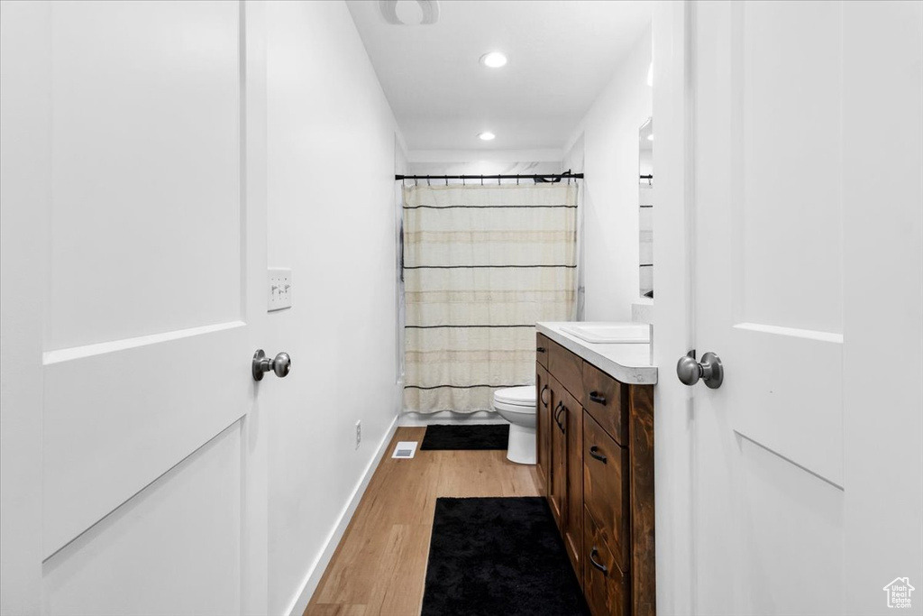 Bathroom with vanity, toilet, recessed lighting, baseboards, and wood finished floors