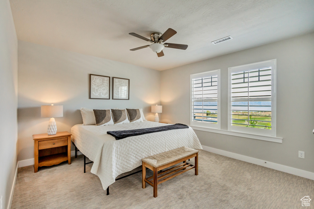 Carpeted bedroom featuring visible vents, baseboards, and ceiling fan