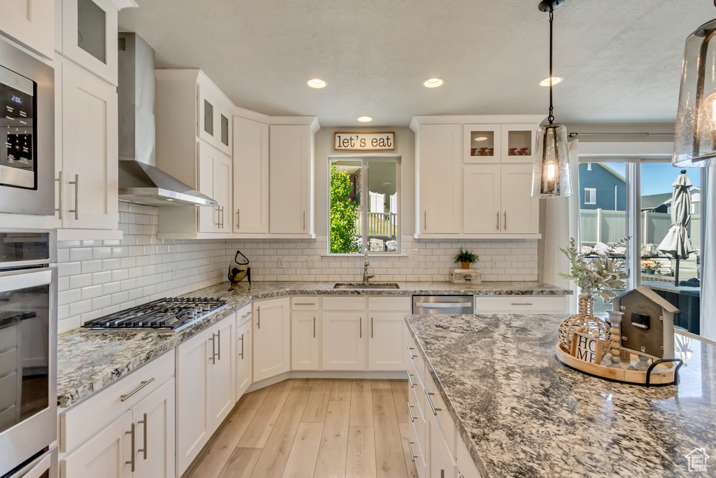 Kitchen with plenty of natural light, a sink, wall chimney exhaust hood, and stainless steel appliances