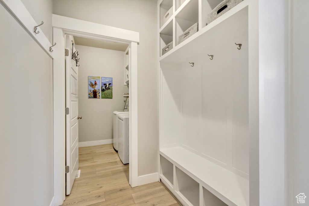 Mudroom with baseboards, light wood finished floors, and washer and dryer