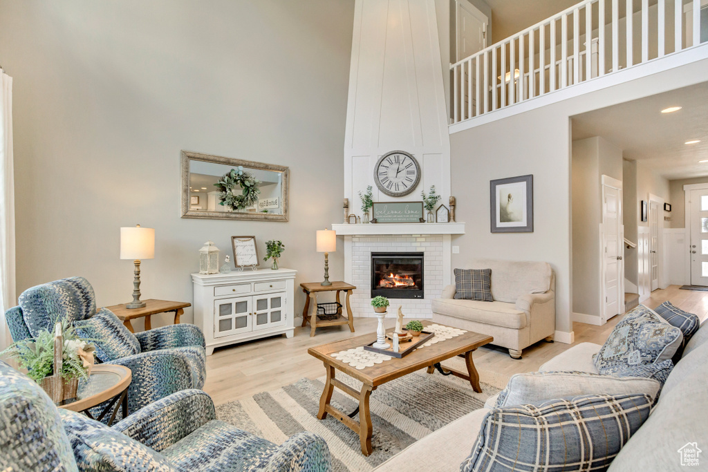Living room featuring a high ceiling, a fireplace, recessed lighting, baseboards, and wood finished floors