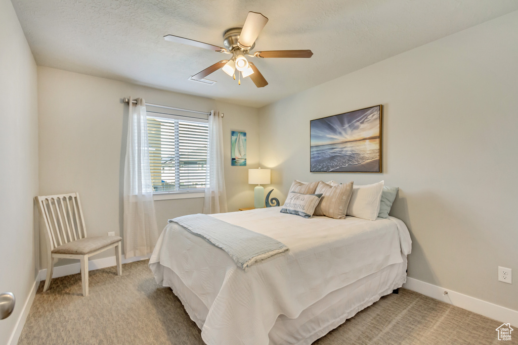 Bedroom with light colored carpet, a ceiling fan, and baseboards