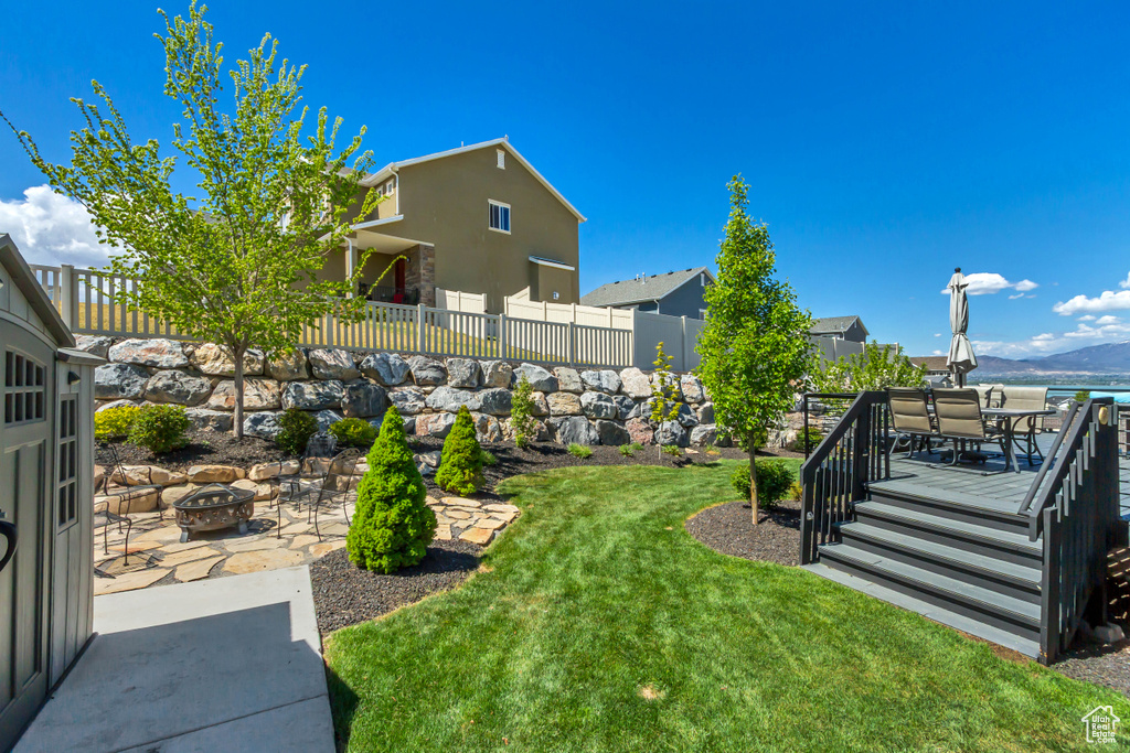 View of yard with fence, outdoor dining space, a mountain view, a patio, and a fire pit