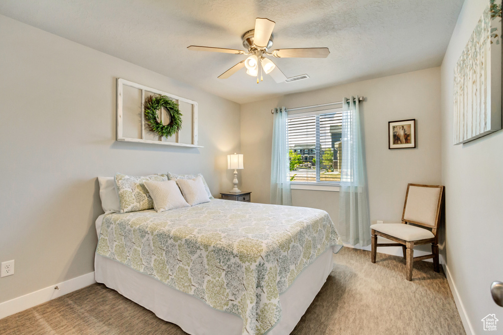 Carpeted bedroom with baseboards, ceiling fan, and visible vents