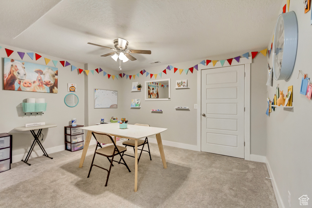 Dining area featuring a ceiling fan, a textured ceiling, and light carpet