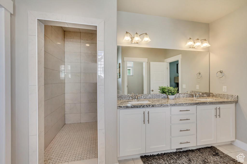 Bathroom featuring double vanity, a sink, a walk in shower, and tile patterned floors