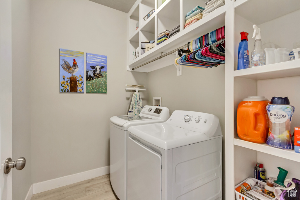 Laundry area featuring laundry area, baseboards, washing machine and dryer, and light wood-type flooring