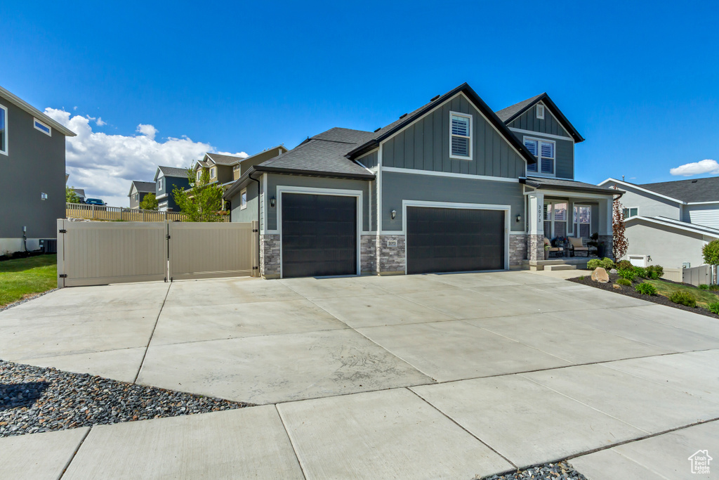 Craftsman house featuring board and batten siding, fence, stone siding, and concrete driveway