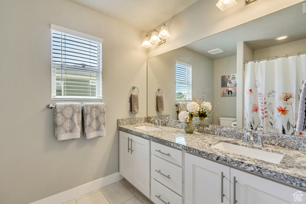 Bathroom with toilet, baseboards, a sink, and tile patterned flooring