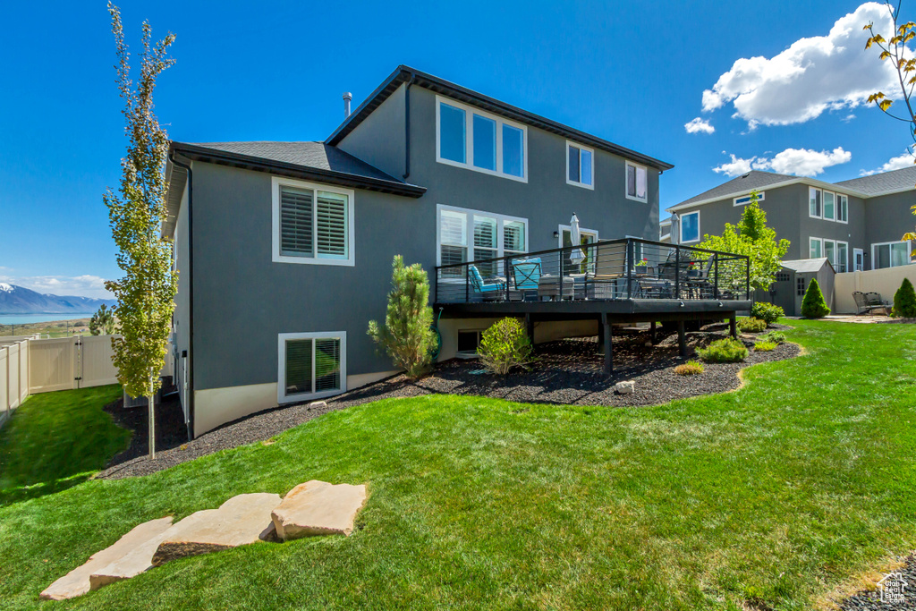 Rear view of property featuring a fenced backyard, stucco siding, a yard, and a deck