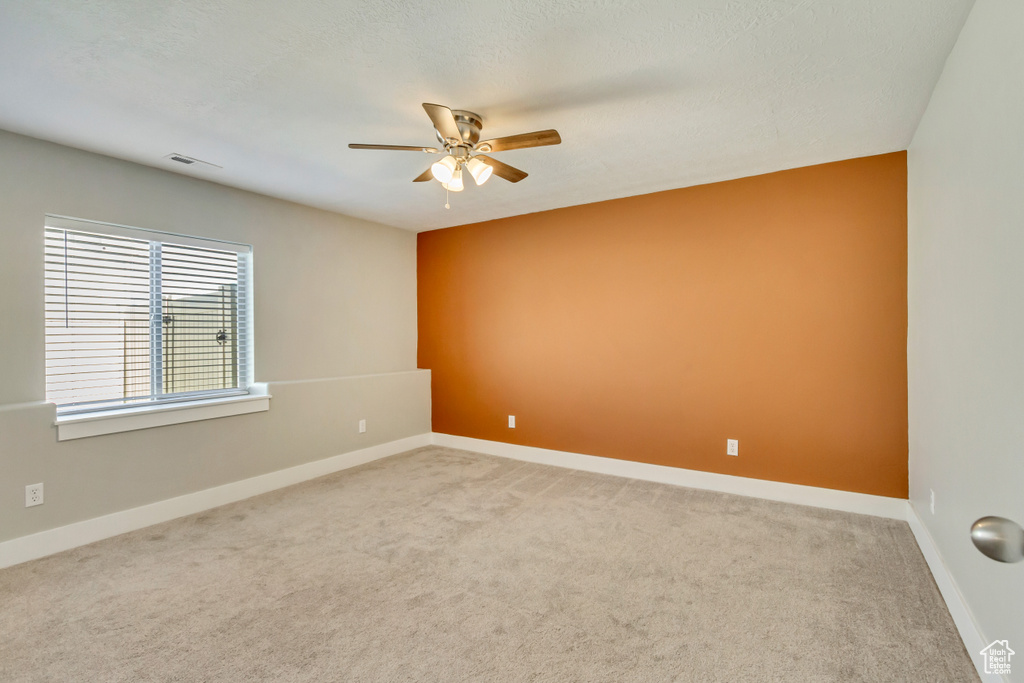 Unfurnished room featuring baseboards, carpet, and a ceiling fan