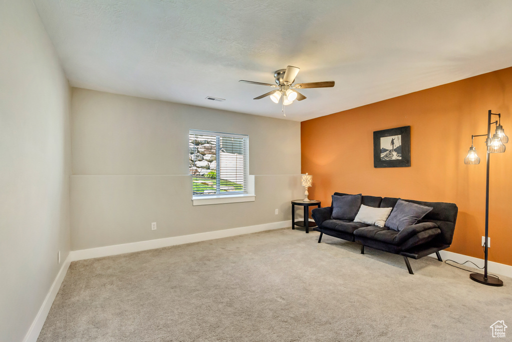 Living area with carpet floors, a ceiling fan, and baseboards