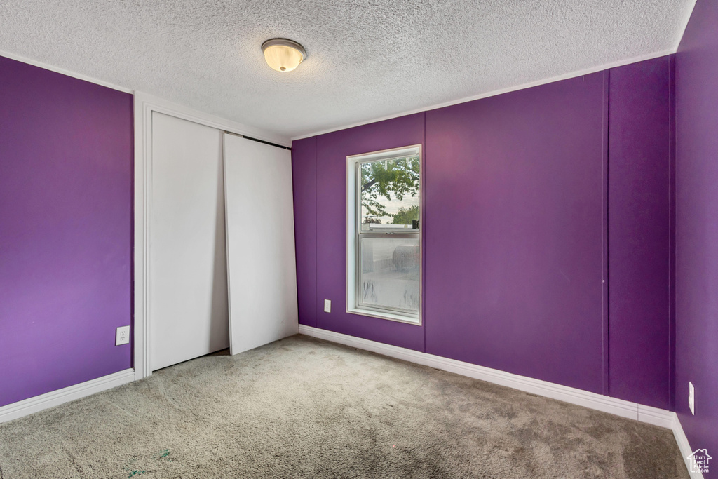 Carpeted spare room featuring baseboards and a textured ceiling