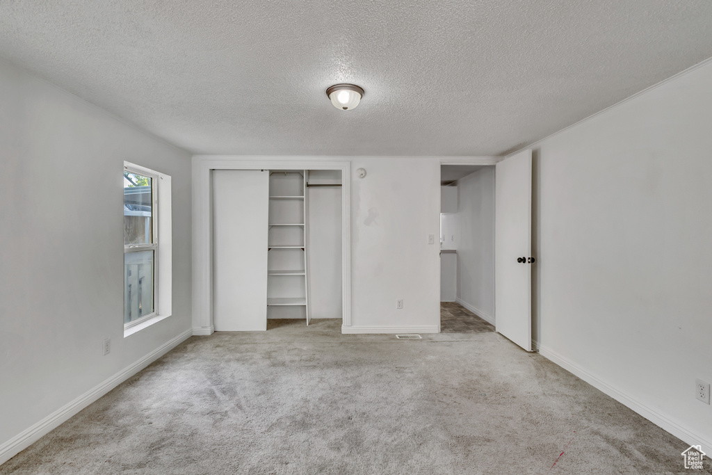 Unfurnished bedroom with carpet floors, baseboards, a closet, and a textured ceiling