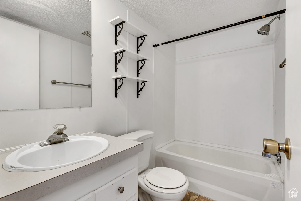 Full bath featuring visible vents, vanity, toilet, a textured ceiling, and shower / washtub combination