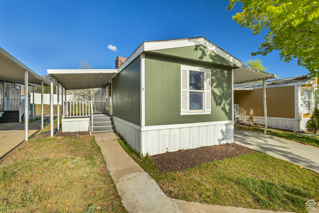 View of front of property with covered porch, a front lawn, and a carport